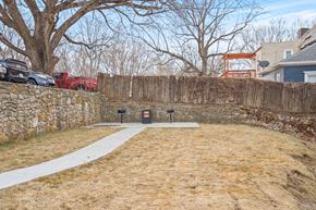 Kansas City apartment for rent - A backyard with a stone wall and a white pathway.