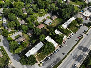 Blue Springs apartment for rent - A bird's eye view of a residential area with houses, trees, and a parking lot.