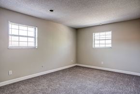 Kansas City apartment for rent - an empty bedroom with two windows and carpeting