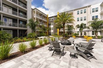 A patio with chairs and a fire pit in front of a building