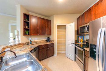 A kitchen with a sink a refrigerator and a stove