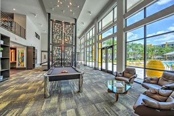 A large room with a pool table and a lot of windows
