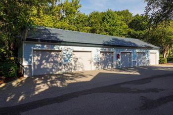 A small blue and white garage with two doors and trees in the background