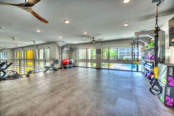A gym with a large window and a ceiling fan