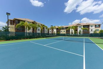A tennis court in front of an apartment complex
