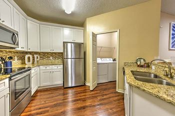 A kitchen with white cabinets and a stainless steel refrigerator