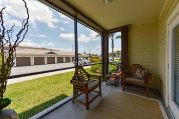 A porch with two chairs and a grassy area