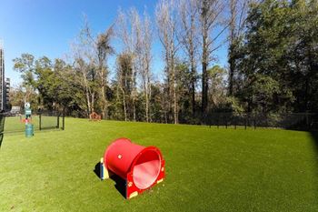 A red trash can sitting on top of a lush green field