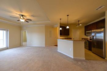 A kitchen and a living room with a ceiling fan