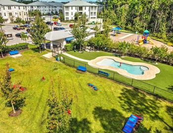 A yard with a pool and a building in the background
