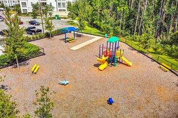A playground in a park with a parking lot in the background