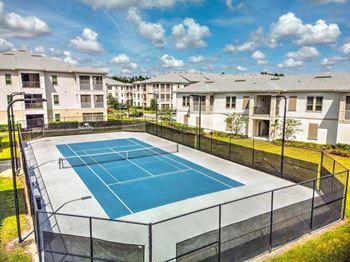 A tennis court with apartments in the background