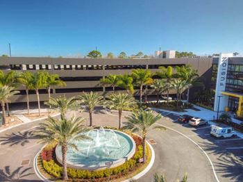 A large building with a fountain in the middle of a parking lot