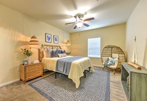 Jacksonville apartment for rent - A bedroom with a bed, a chair, and a ceiling fan at Cabana Club - Galleria Club Apartments, Florida 32256