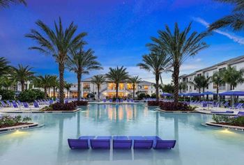 A resort style pool with lounge chairs and palm trees