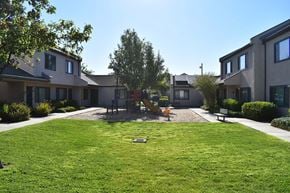 Davis townhouse for rent - A playground with a slide is surrounded by houses and green grass.