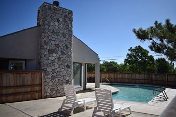Davis townhouse for rent - Two chairs are placed on a patio in front of a stone pillar and a pool.