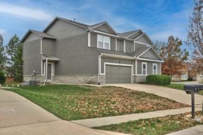 Olathe triplex for rent - a gray house with a driveway and a parking meter in front of it