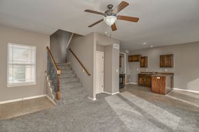 Olathe triplex for rent - A living room with a staircase and a ceiling fan.