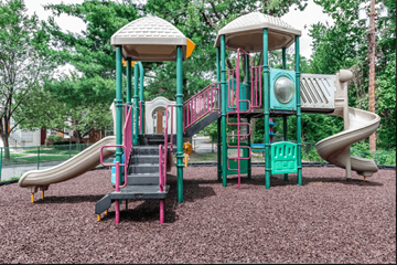 Parsippany apartment for rent - A playground with a green and pink slide and a white and green tower.