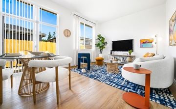Bend apartment for rent - A living room with a white couch, a wooden table and chairs, a TV, and a plant.