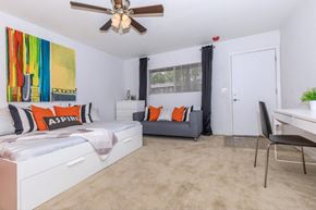 Tucson apartment for rent - A bedroom with a bed, a chair, and a painting on the wall.