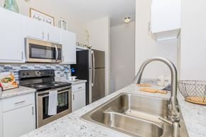 Tucson apartment for rent - A kitchen with a stainless steel sink and white cabinets.