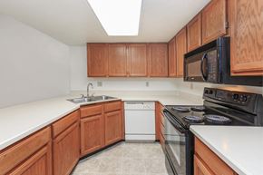 Tucson apartment for rent - A kitchen with wooden cabinets and a black microwave above the stove.