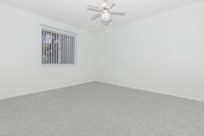Tucson apartment for rent - A room with a ceiling fan and a window with bars.