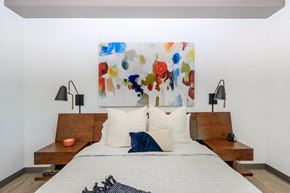 Tucson apartment for rent - A bedroom with a large painting on the wall and a bed with white bedding.