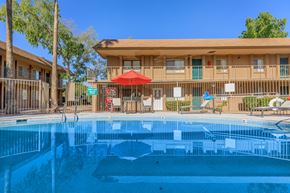 Tucson apartment for rent - A swimming pool in front of a building with a red umbrella.