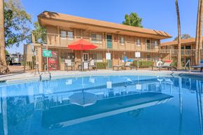 Tucson apartment for rent - A swimming pool in front of a building with a red umbrella.