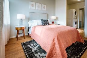 Portland apartment for rent - A bedroom with a pink bedspread and a black and white rug.