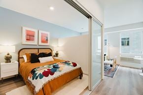 Portland apartment for rent - A bedroom with a bed, two lamps, and a painting on the wall.