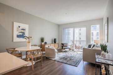 Shoreline apartment for rent - A living room with a white table and chairs, a couch, a rug, and a painting on the wall.