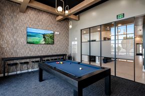 Kennewick apartment for rent - A pool table with a television on the wall and a green exit sign above it.