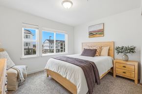 Richland apartment for rent - A bedroom with a large bed, a window with a view of a house, and a potted plant on the nightstand.
