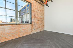 Tucson apartment for rent - A room with a large window and a brick wall.
