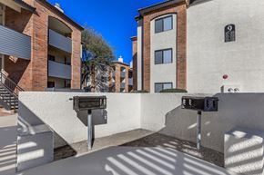 Tucson apartment for rent - A parking meter is in front of a building with a tree in the background.