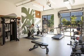 Gresham apartment for rent - Arts Plaza Gresham Oregon Apartments fully equipped fitness center with a woman working out on a treadmill.