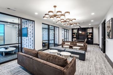 Lewisville apartment for rent - A modern living room with a brown sofa and a chandelier.