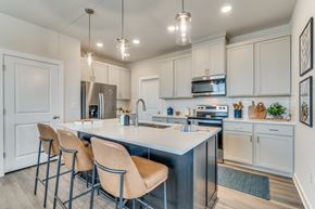 Leander apartment for rent - an open kitchen with white cabinets and a large island with four stools
