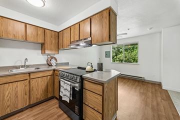 Gresham apartment for rent - A kitchen with wooden cabinets and a black stove top oven.