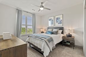 Kyle apartment for rent - A bedroom with a bed, nightstand, and a ceiling fan.