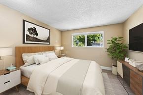 Eugene apartment for rent - A bedroom with a large bed, a nightstand, a lamp, a plant, and a framed picture of a tree on the wall.