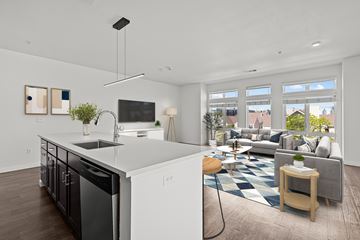 Denver apartment for rent - A modern kitchen with a large island and a living room with a couch and a coffee table.