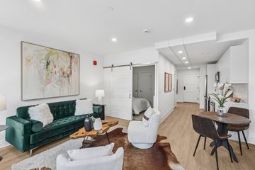 Silver Spring apartment for rent - A living room with a green couch, white chairs, and a painting on the wall.