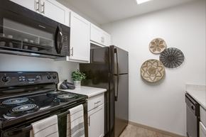 Tucson apartment for rent - A black stove top oven with a white counter top and a black refrigerator in a kitchen.