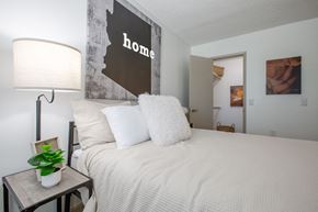 Tucson apartment for rent - A bedroom with a bed, lamp, and a picture of a woman.