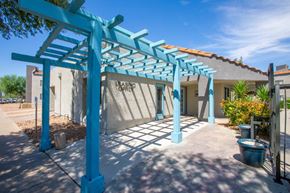 Tucson apartment for rent - A blue pergola is in front of a building with the words "Leasing Office" on it.